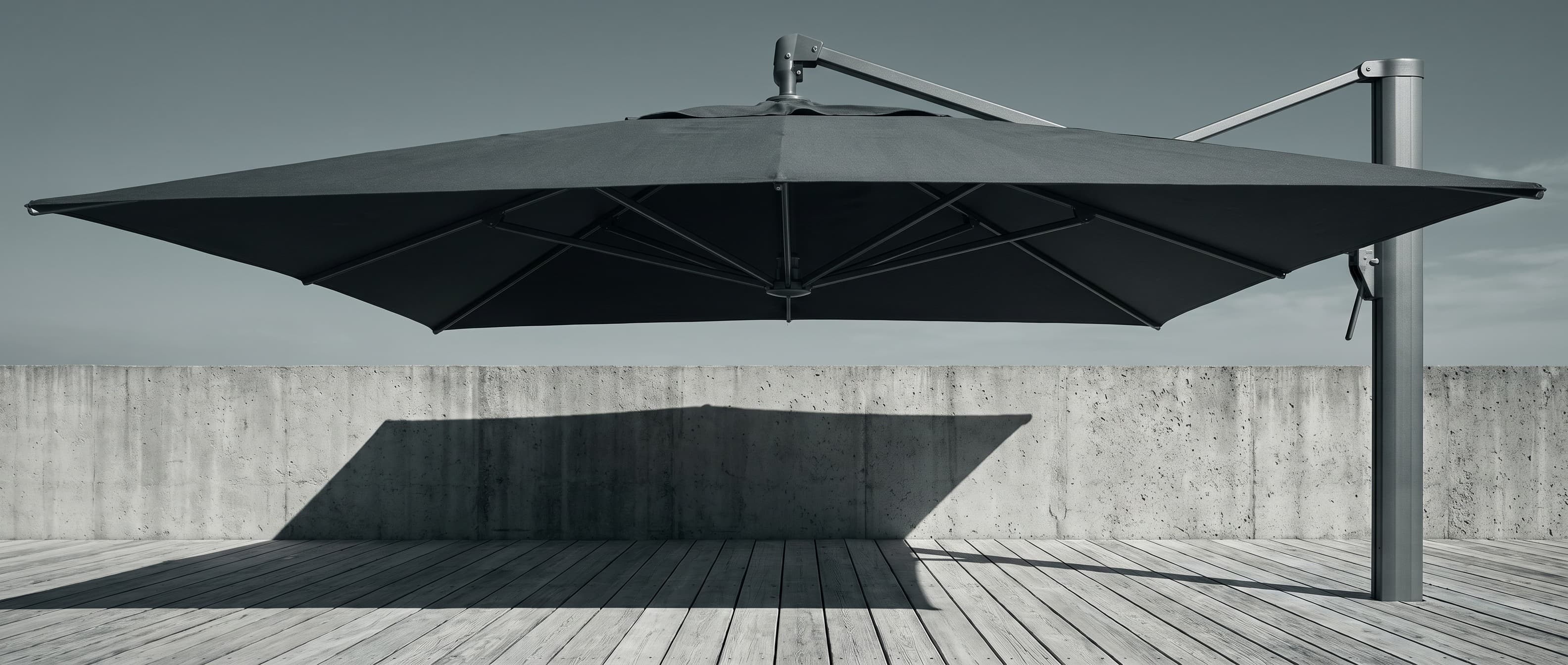 Ombrelone lateral de lona escura visto de baixo, com haste e ferragens em alumínio, projetando sombra sobre uma parede de concreto e um deck de madeira, imagem de referência.